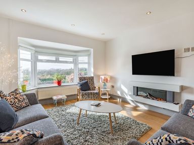 A living room with sofas armchair coffee table wall mounted TV and electric fireplace at Bryn Derw in Caernarfon