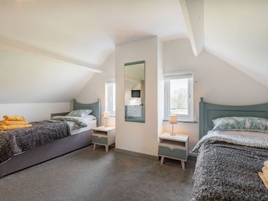A bedroom with two single beds bedside tables and lamps at Bryn Derw in Caernarfon