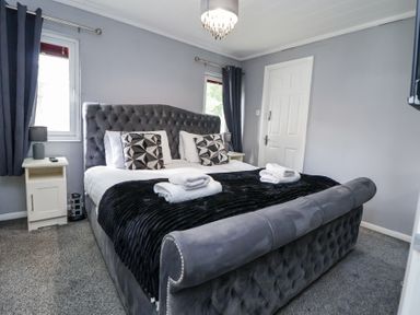 A bedroom with a large bed with pillows and folded towels with bedside tables and lamps at 155 Woodland Hall Lyons Ruthin