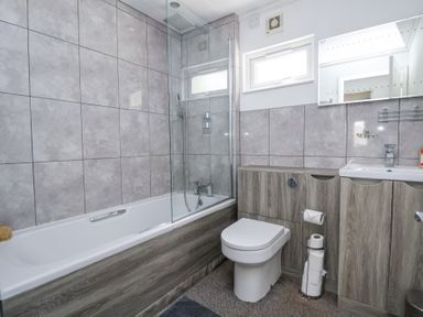 A bathroom with a bathtub shower toilet and sink with cabinets at 155 Woodland Hall Lyons in Ruthin
