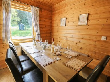A dining room with a table set for dinner at Dan Y Coed near Beggar's Bush