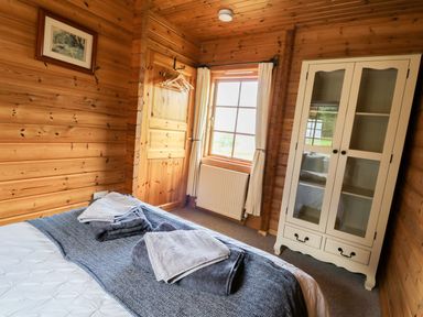 A bedroom with a bed and wardrobe at Dan Y Coed near Beggar's Bush