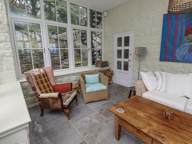 A conservatory with seating and a wooden table at Elford Farmhouse in Seahouses