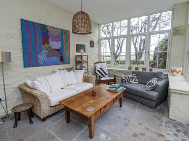 A sunroom with a sofa and coffee table at Elford Farmhouse in Seahouses