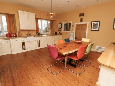 A kitchen with a dining table and colorful chairs at Elford Farmhouse in Seahouses