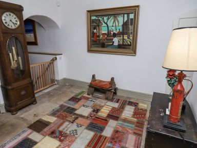 A hallway with a clock and rug at Elford Farmhouse in Seahouses