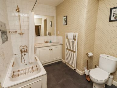 A bathroom with a bathtub and sink at Elford Farmhouse Seahouses