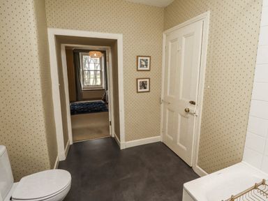 A bathroom with a toilet and door at Elford Farmhouse in Seahouses