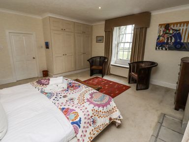A bedroom with a bed and wardrobe at Elford Farmhouse in Seahouses