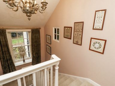 A staircase with chandelier and framed artwork at Elford Farmhouse in Seahouses