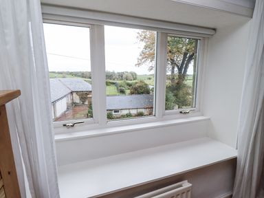 A window with a view of a field and buildings at Elford Farmhouse in Seahouses
