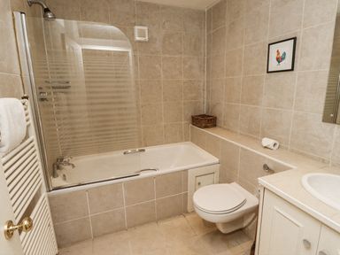 A bathroom with a bathtub and a toilet at Elford Farmhouse Seahouses