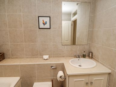 A bathroom with a sink and mirror at Elford Farmhouse in Seahouses