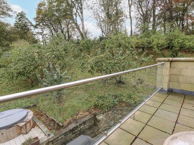 An outdoor area with a hot tub and balcony overlooking a garden at Elford Farmhouse in Seahouses