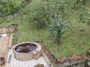 A garden with a hot tub and trees at Elford Farmhouse in Seahouses