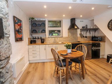 A kitchen with wooden dining table and chairs and appliances at 4 Old Tanrhiw in Beddgelert