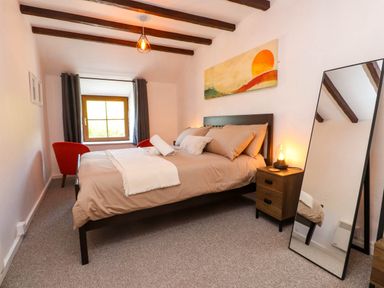 A bedroom with a bed bedside table with lamp mirror and window at 4 Old Tanrhiw in Beddgelert