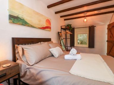 A bedroom with a bed a bedside table a standing mirror a window and a rack at 4 Old Tanrhiw in Beddgelert