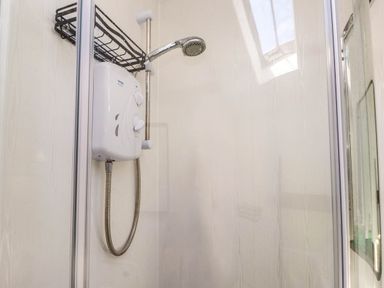 A close up of a shower unit with a showerhead and metal shower hose inside a shower cubicle at 4 Old Tanrhiw in Beddgelert