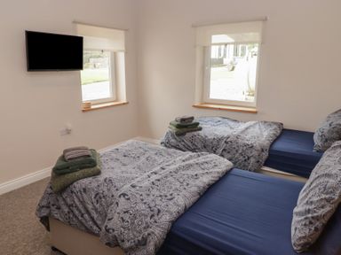 A bedroom with two beds and a television at The Lodge in Bridgend