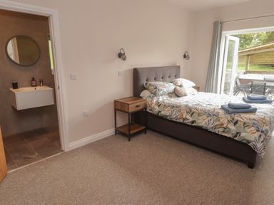A bedroom with a bed and bathroom sink at The Lodge in Bridgend