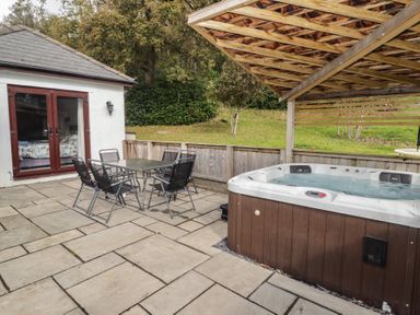 An outdoor space with a jacuzzi and seating area at The Lodge in Bridgend