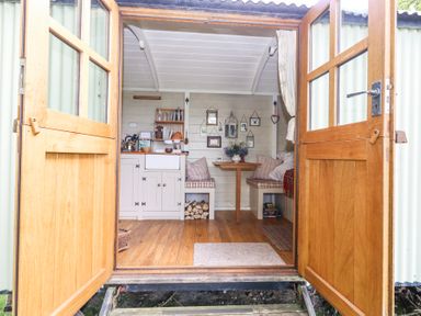 A small kitchen and dining area with wooden floors and open double doors at Sika in Warmwell