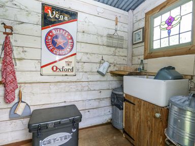A utility room with a sink a stained glass window a red cloth a wall sign and metal trash bins at Fallow Warmwell