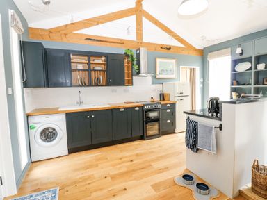 A kitchen with black cabinets wooden beams wooden floor a washing machine oven and refrigerator at The Barn in Riding Mill near Corbridge