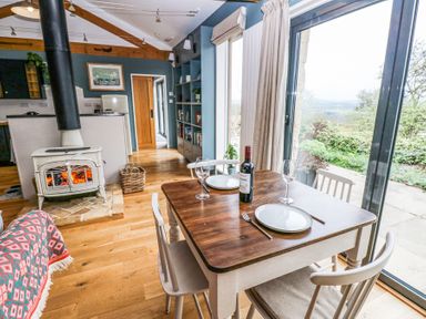 A dining table with wine and plates next to a wood stove and large window at The Barn in Riding Mill near Corbridge