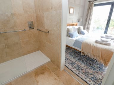 A tiled shower area next to a bedroom with a bed and a patterned rug at The Barn in Riding Mill near Corbridge