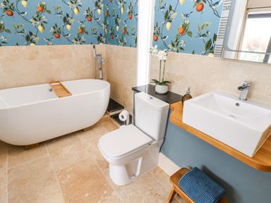 A bathroom with a freestanding bathtub toilet sink and floral wallpaper at The Barn in Riding Mill near Corbridge