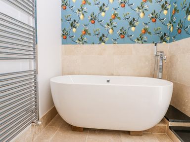 A bathroom with a freestanding bathtub against a tiled wall with a patterned upper section at The Barn in Riding Mill near Corbridge
