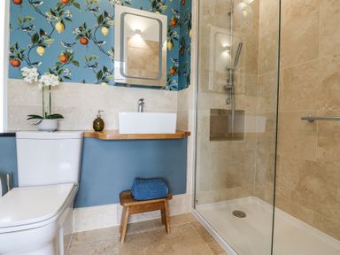 A bathroom with a toilet a sink mirror glass shower and stool with towel at The Barn Riding Mill near Corbridge