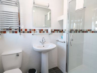 A bathroom with a toilet sink mirror and glass shower enclosure at The Burleigh in Hunstanton