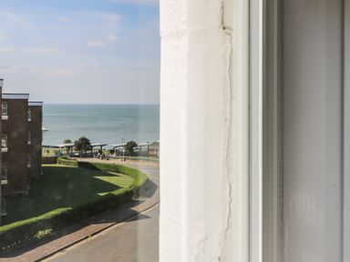 A view of the sea and a lawn with shrubs near a road seen through a window at The Burleigh in Hunstanton