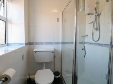 A bathroom with a toilet and a glass shower enclosure at The Burleigh in Hunstanton