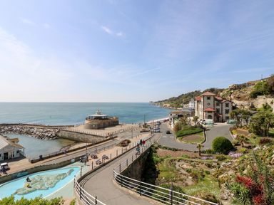 A coastal walkway with people near a small harbor and gardens by the sea at Moonlight in Ventnor