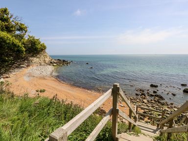 A wooden staircase leading down to a rocky and sandy beach with the sea and sky in the background at Moonlight in Ventnor