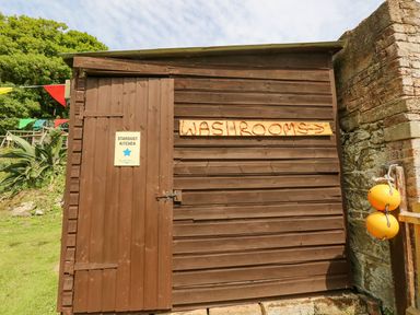 A brown wooden building with signs for Stardust Kitchen and washrooms outdoors at Stardust in Ventnor