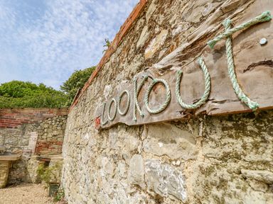 A stone wall with a wooden sign displaying the word The Lookout made of rope at Stardust in Ventnor