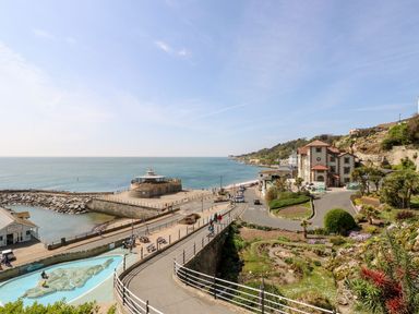 A coastal scene with a walkway along the sea and buildings near the shore at Stardust in Ventnor