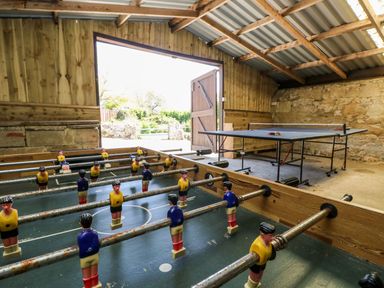 A foosball table and a ping pong table inside a wooden game room at Stardust in Ventnor