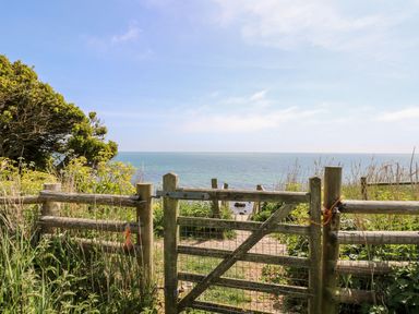 A wooden gate opening to a path leading to the sea with vegetation on either side at Stardust in Ventnor