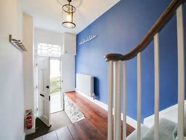 A hallway with a bench and a staircase at Church Hill House in Port Isaac