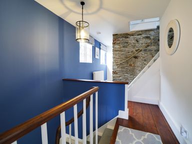 A staircase with a blue wall and light fixture at Church Hill House in Port Isaac