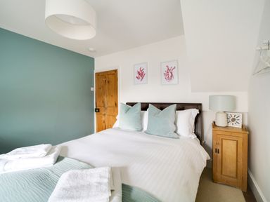 A bedroom with a bed and wall art at Church Hill House in Port Isaac