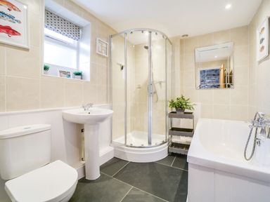 A bathroom with a shower, bathtub, sink, and toilet at Church Hill House in Port Isaac