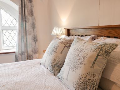 A bed with tree patterned pillows and matching curtains next to a window at Dwynant in Bontddu near Dolgellau