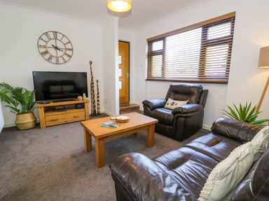 A living room with brown leather sofas wooden coffee table flat screen TV and wooden blinds at Gilfach Bach in Dolgellau